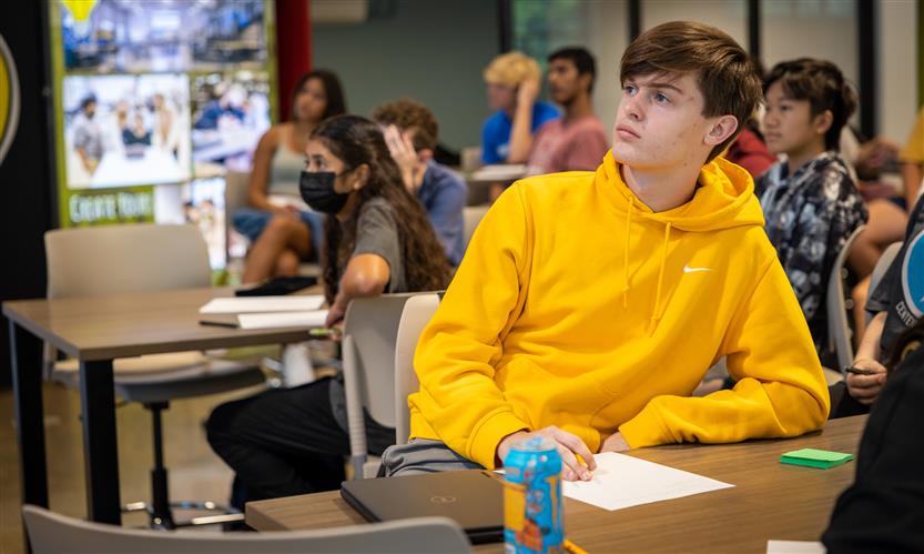 A boy looks up at a presenter while sitting at a table